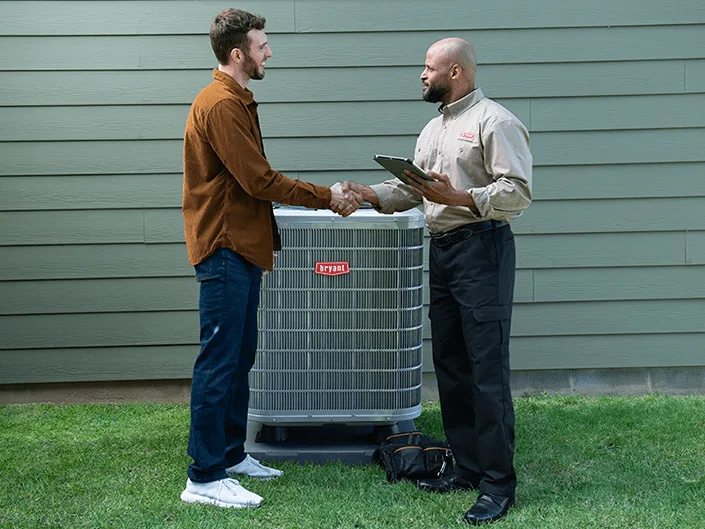 A Bryant dealer and a homeowner shake on the plan at the outdoor unit